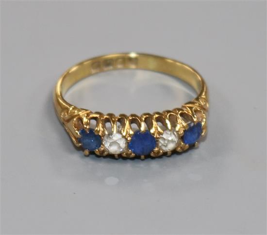 An Edwardian 18ct gold, sapphire and diamond five stone half hoop ring, size M.